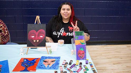 Student flashing a peace sign tabling at the art market at Bear Fest 2025.
