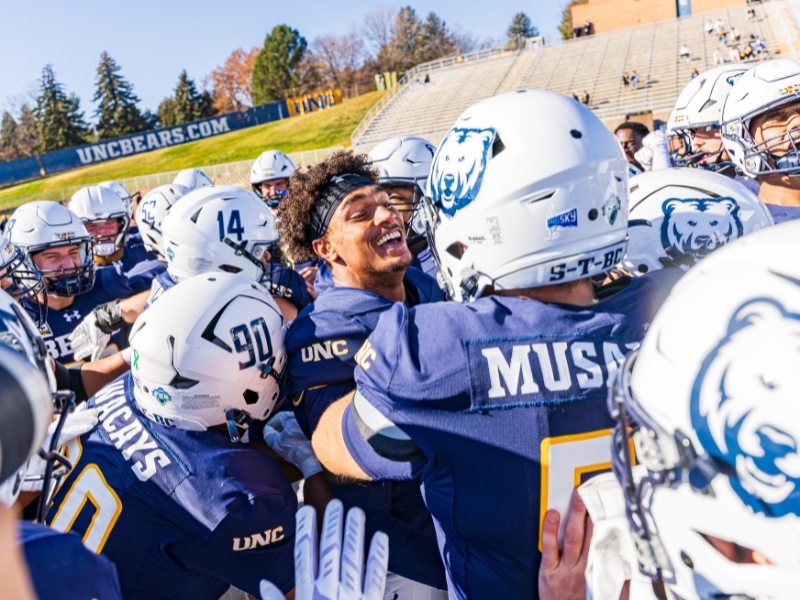 UNC Bear football players celebrating in a huddle
