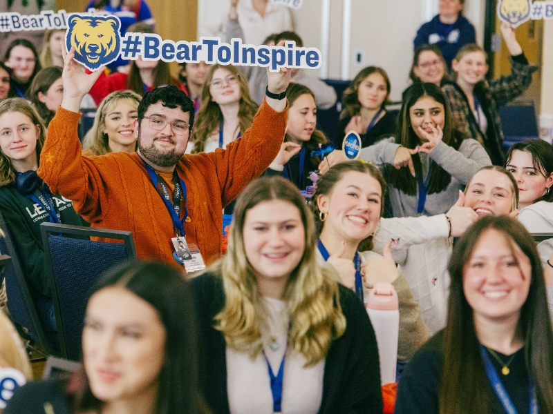 Attendees of the Future Teacher Conference hold up banners saying 