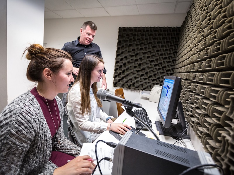Two female students receiving instruction in an audiology lab.
