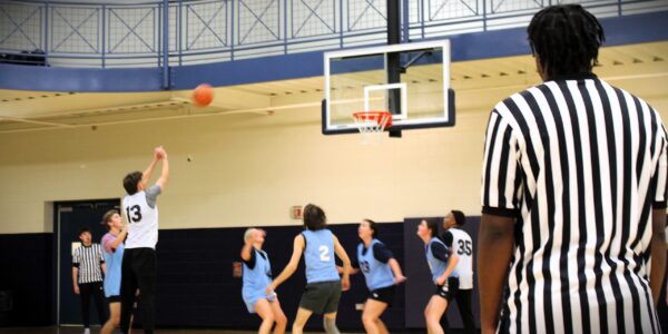 Students playing Intramural Basketball with a student official observing a free throw.