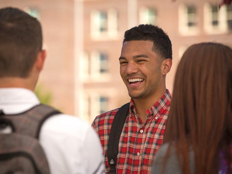 Male student laughing with friends on campus.