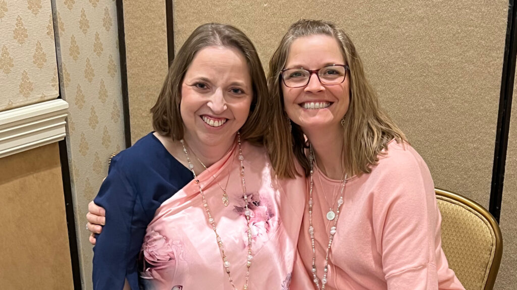 Two sisters with their arms wrapped around each other smiling