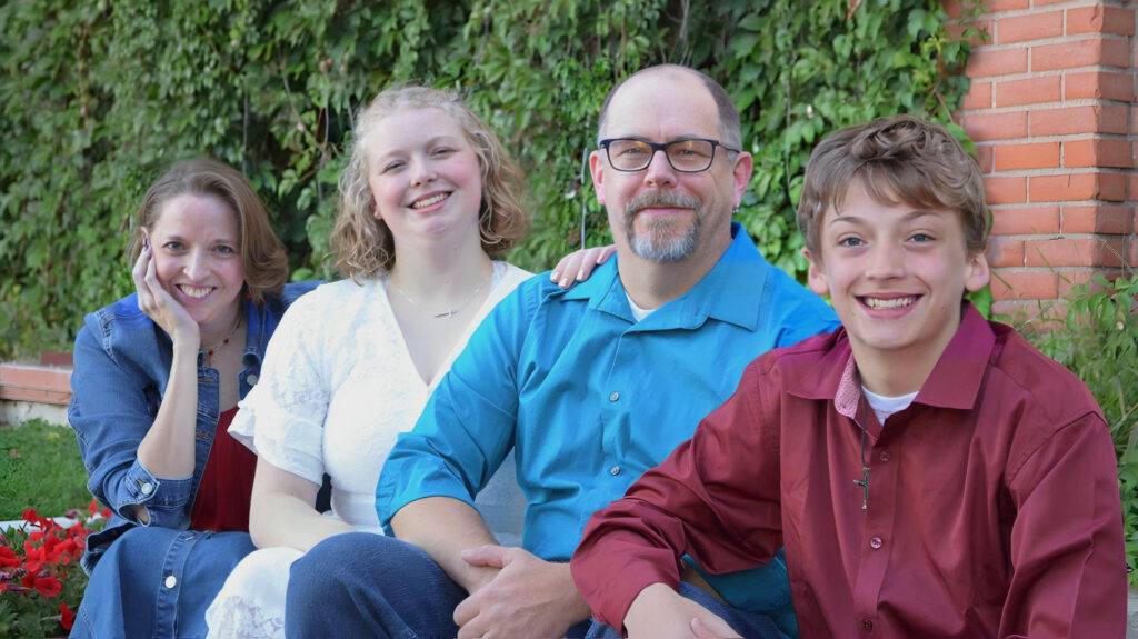 A mother, daughter, father and son sitting next to each other outside