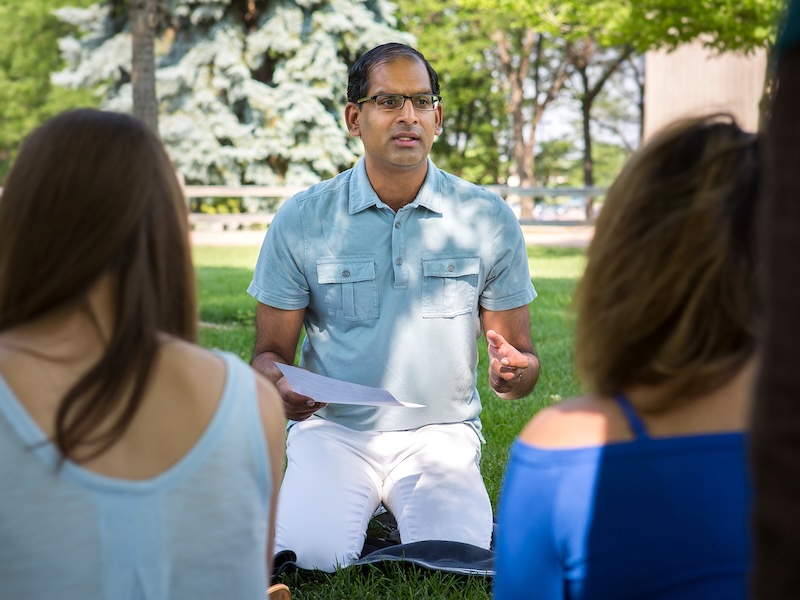 Hispanic man teaching graduate students outside on a sunny day