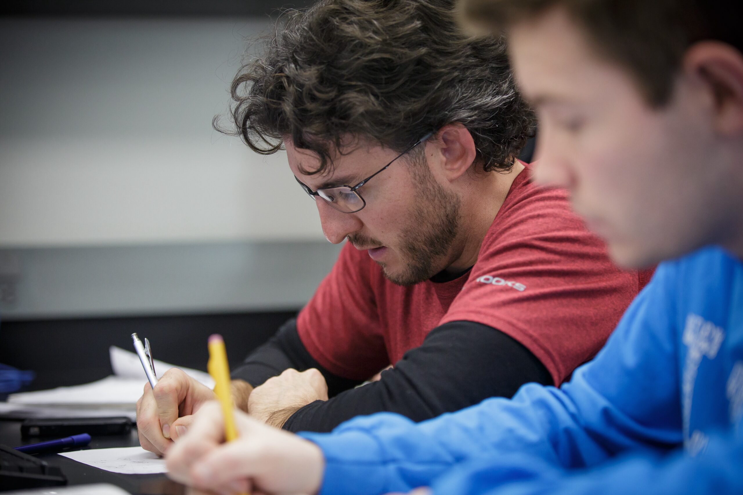 Two male students writing in a class.