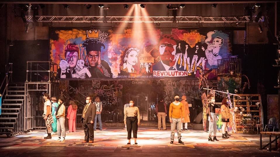 A group of UNC students standing on the Rent stage wearing masks