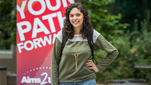 Student standing in front of a sign that says 