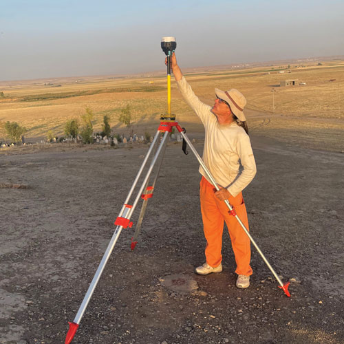 Andy Creekmore holding equipment that looks like a tripod in a field