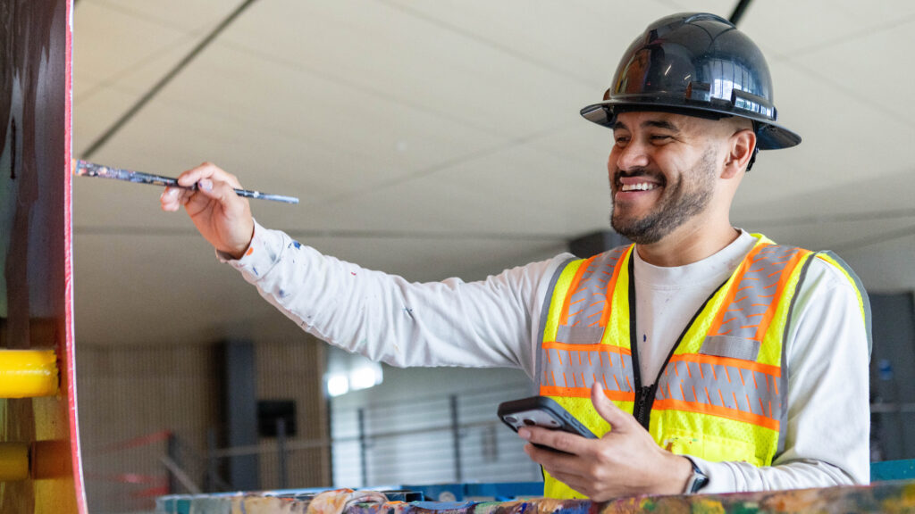 Armando Silva painting and smiling wearing a hard hat
