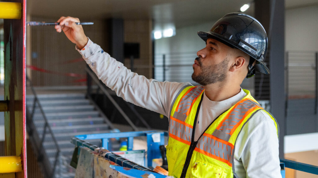 Armando Silva painting his mural inside the College of Osteopathic Medicine building