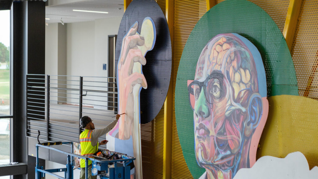 Armando Silva painting his mural inside the College of Osteopathic Medicine building