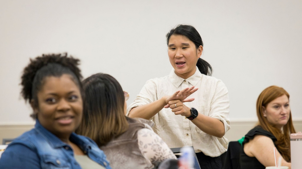 A person speaking in American Sign Language in a room at an ASL conference at UNC.