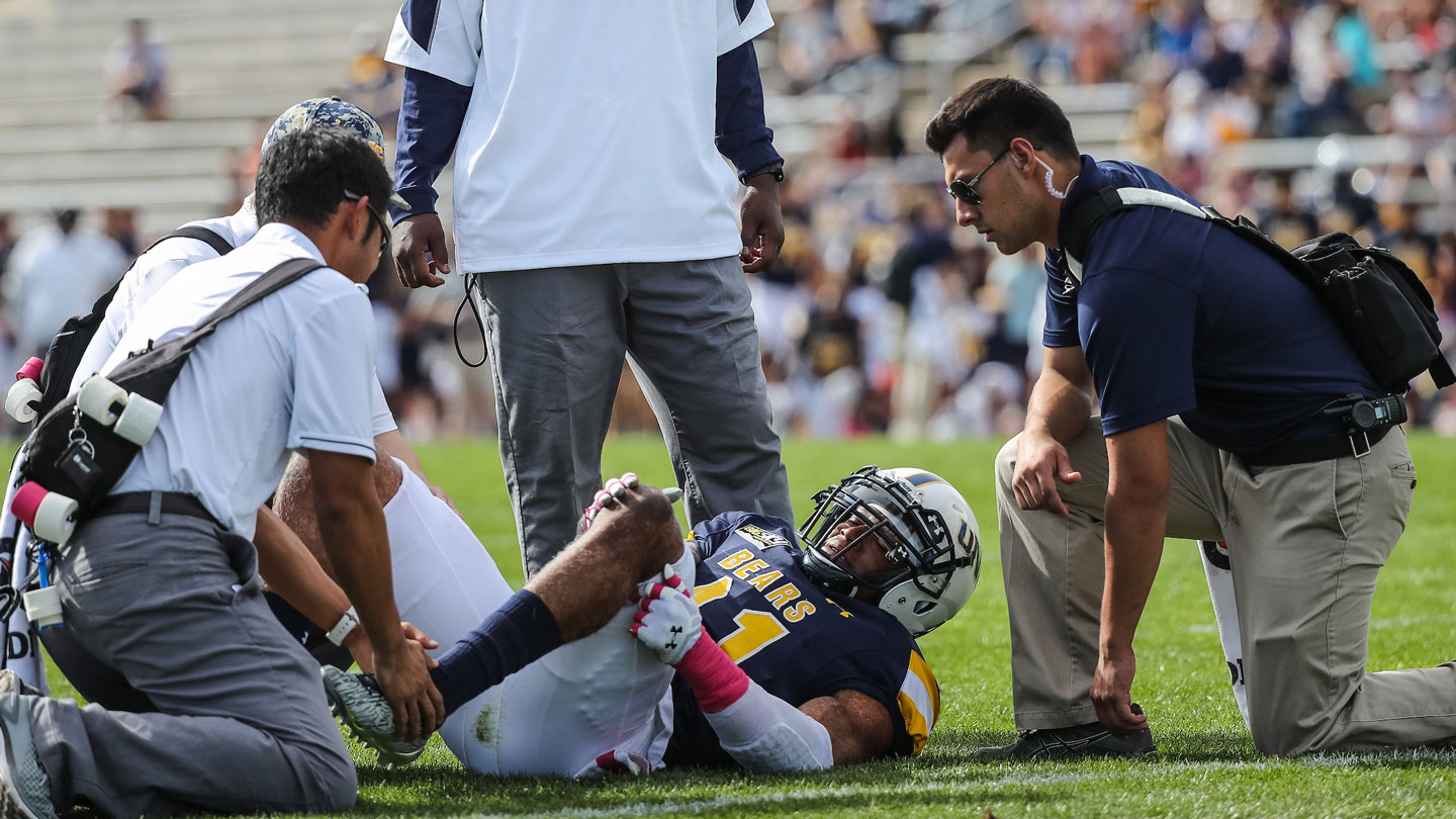 Athletic trainers tending to a football player on the ground.