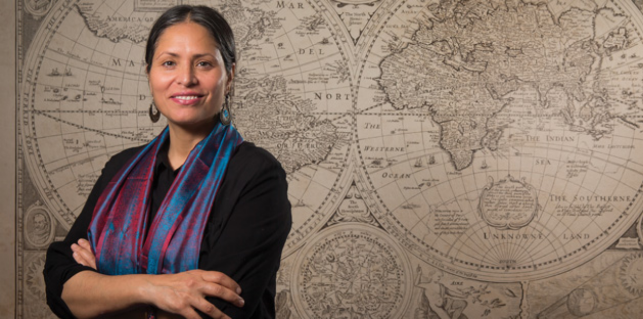 Professor Ather Zia standing in front of an antique map of the world.
