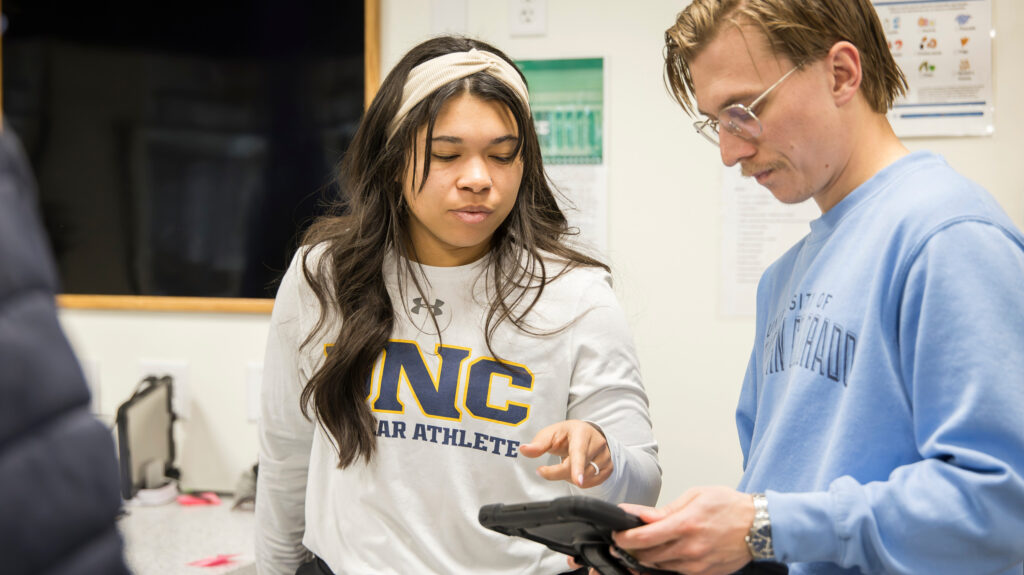 Freddie Horn and Taylor Schiestel looking at an i-pod