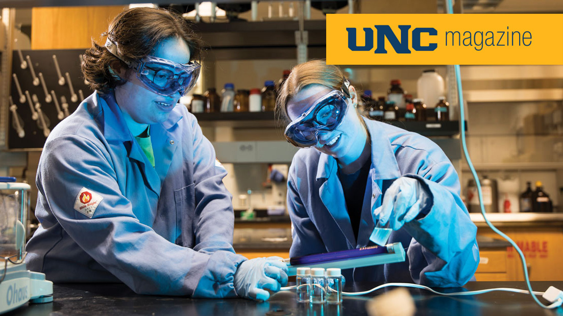 Two students in lab gear working on a science project
