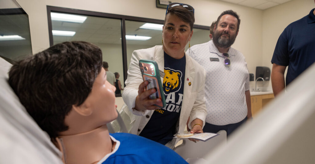 A physician taking a picture of a fake person inside the College of Osteopathic Medicine building