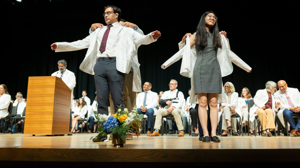 Two medical student on stage getting white coated