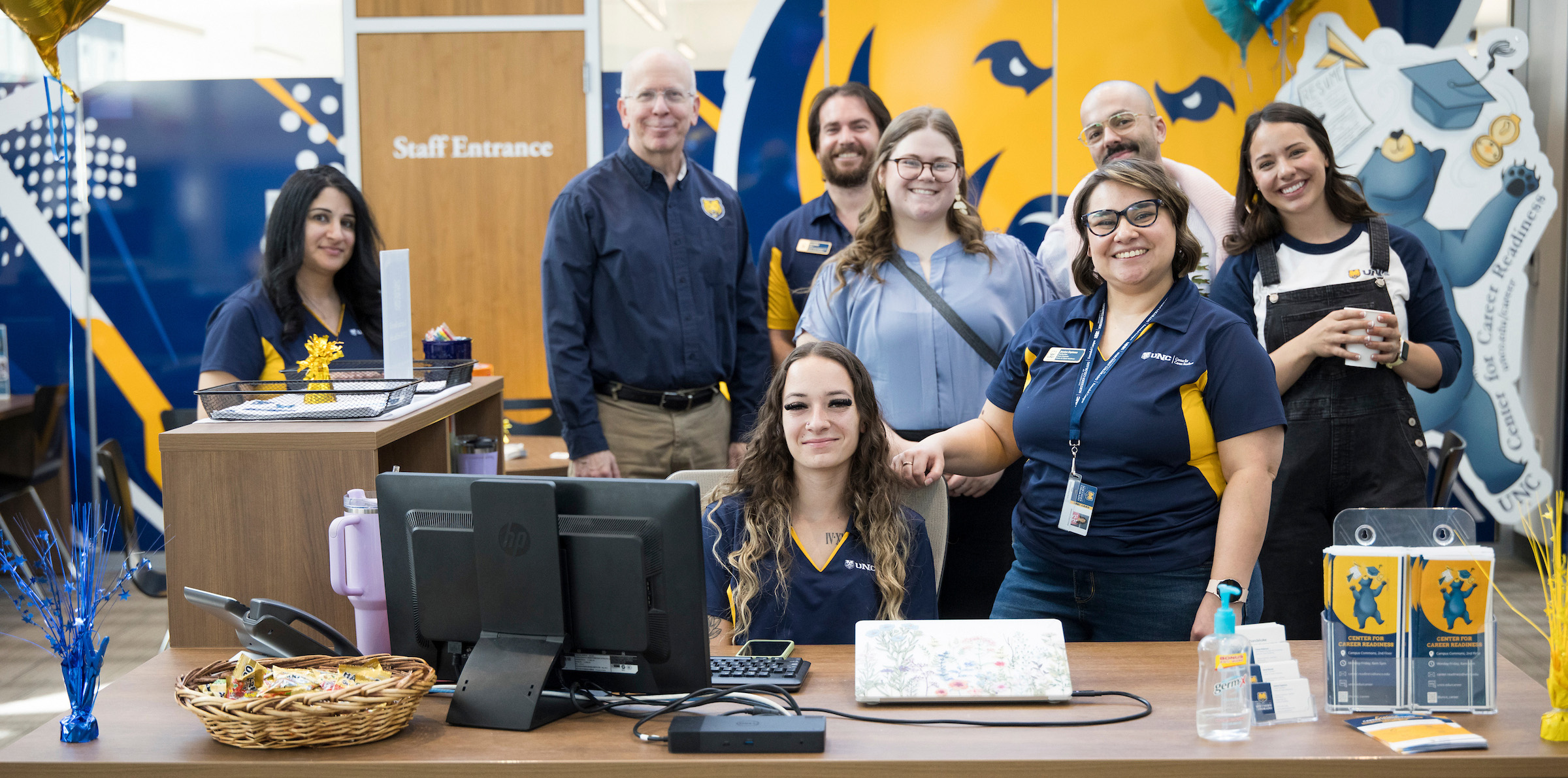 A group of people working in Career Readiness standing behind a desk and smiling