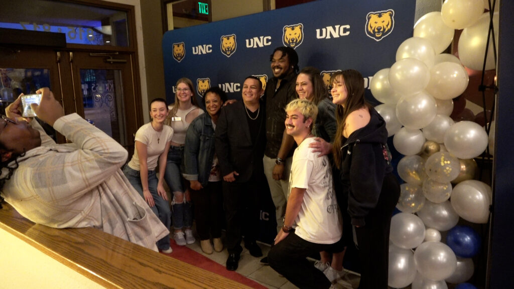 Carlito Hale is surrounded by fellow UNC students in front of a UNC backdrop