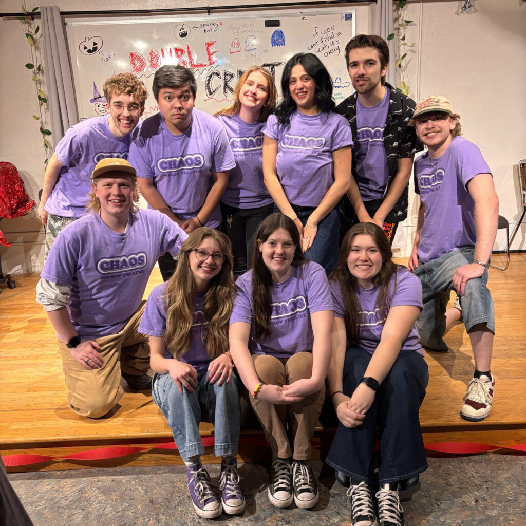 A group of students smiling together wearing purple shirts that say Choas on them