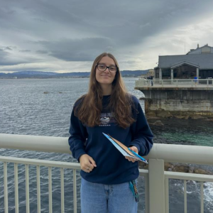 UNC student Colbi Heineman standing in front of the ocean.