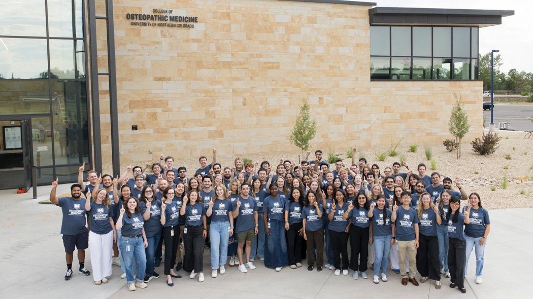 Members of the first class of the College of Osteopathic Medicine, standing outside the building in a group.