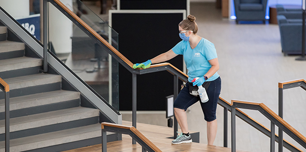 A custodial staff member is cleaning the stairs handle