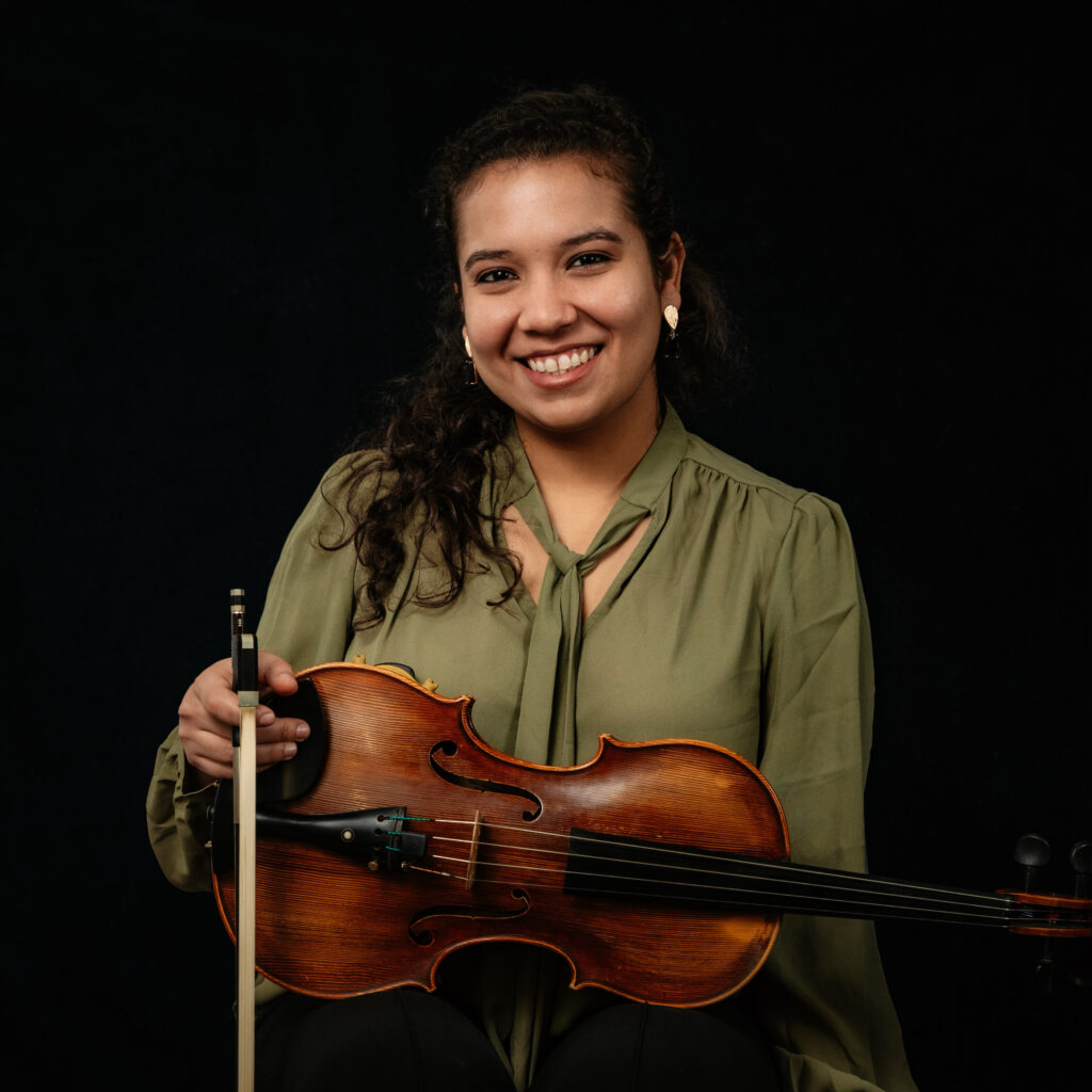Daniella Martinez holding a violin and smiling at the camera