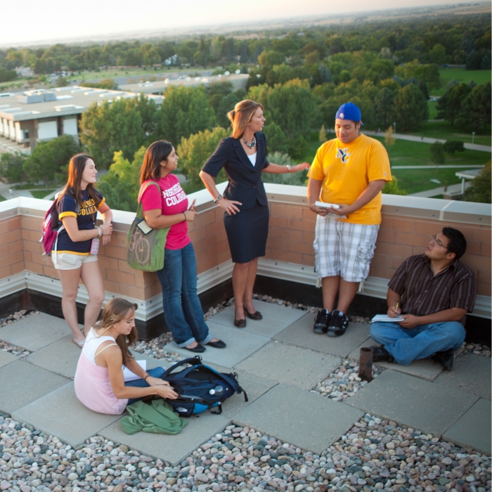 A group of students on the rooftop patio with UNC in the background