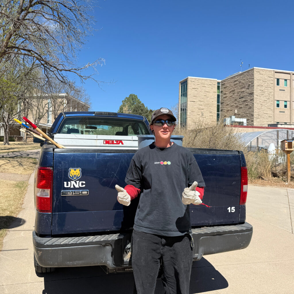Freddy Lee standing in front of a navy truck doing two thumbs up