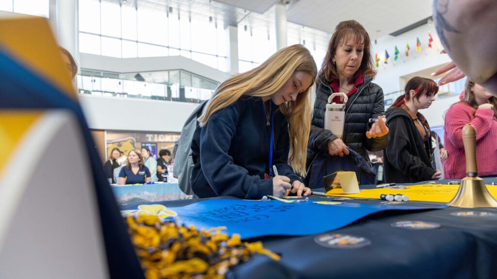 a high school student writing on a paper at a fair during the Future Teacher Conference 2026