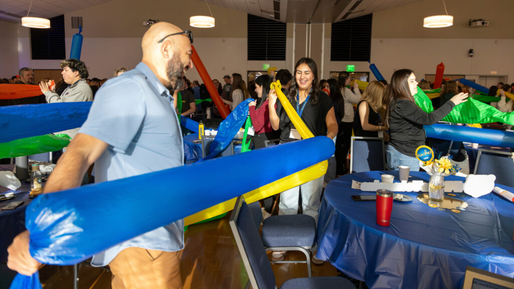 A group of people holding up long balloons at the Future Teacher Conference