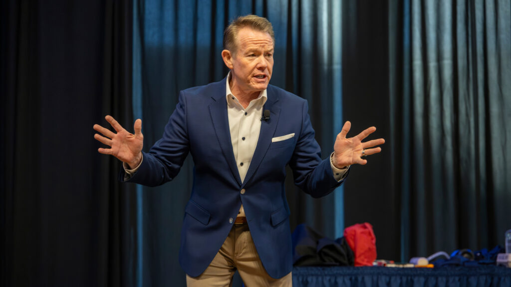 Steve Spangler speaking with his hands out on a stage
