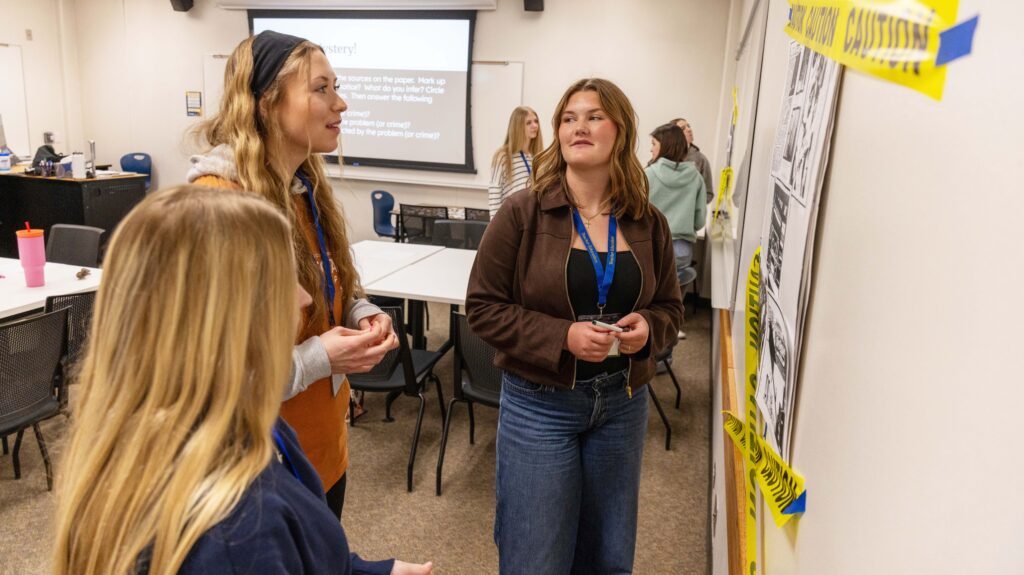 Three students looking at a paper on the wall