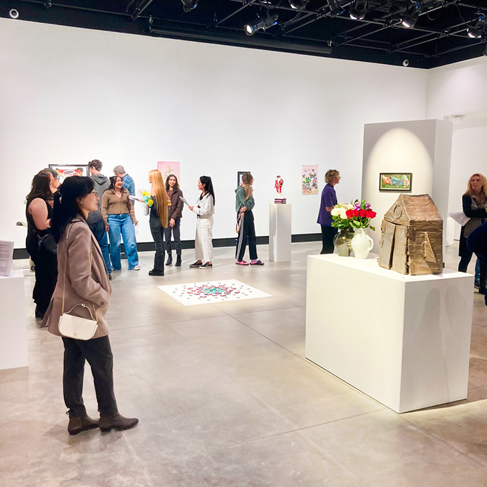 Several people viewing the Annual Student Juried Exhibition in the Ruyle Gallery at UNC.