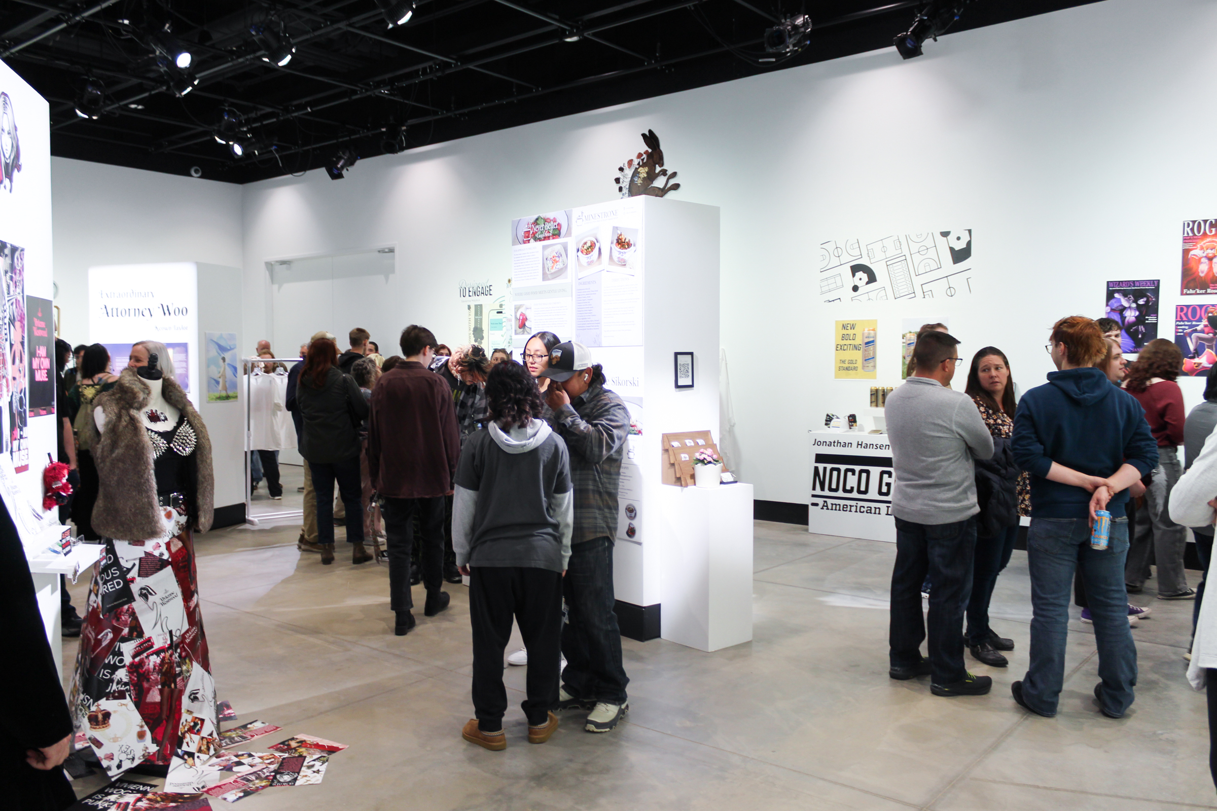 A group of people viewing the Graphic Design Senior Show in Ruyle Gallery at UNC.