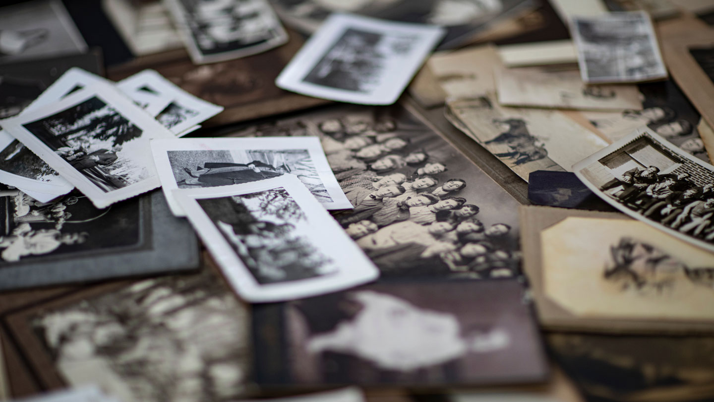 Multiple, scattered old photos of people.