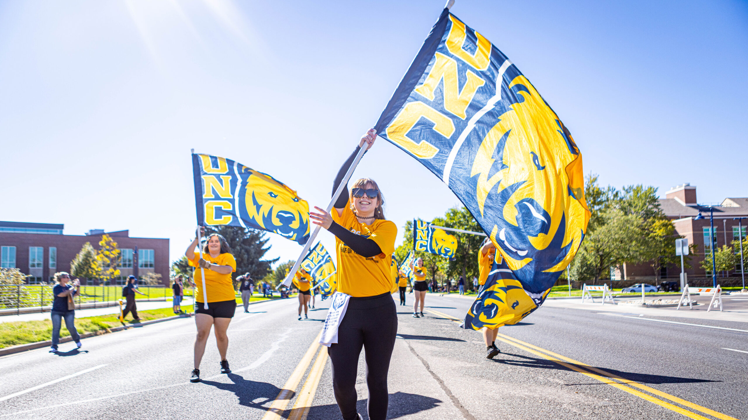 Two people waving UNC flags in the street during a parade