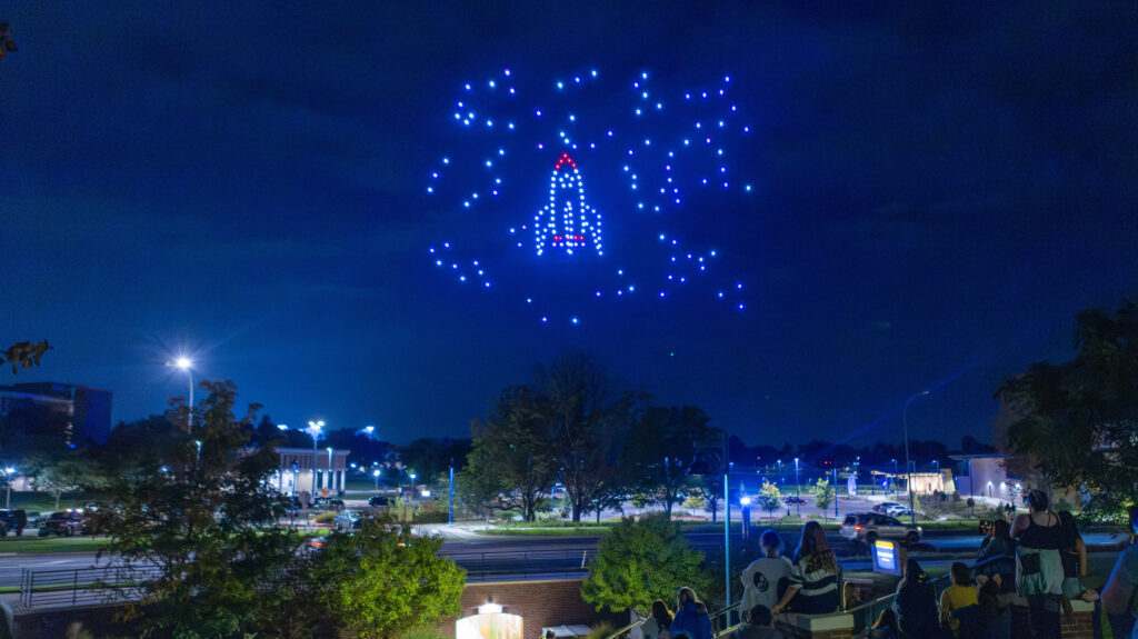 A spaceship lit in the sky by drones