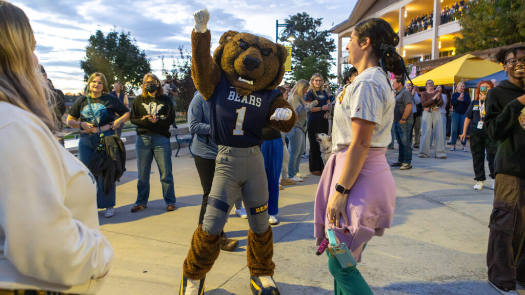 UNC's mascot, Klawz, punching his right fist in the air surrounding by a group of people