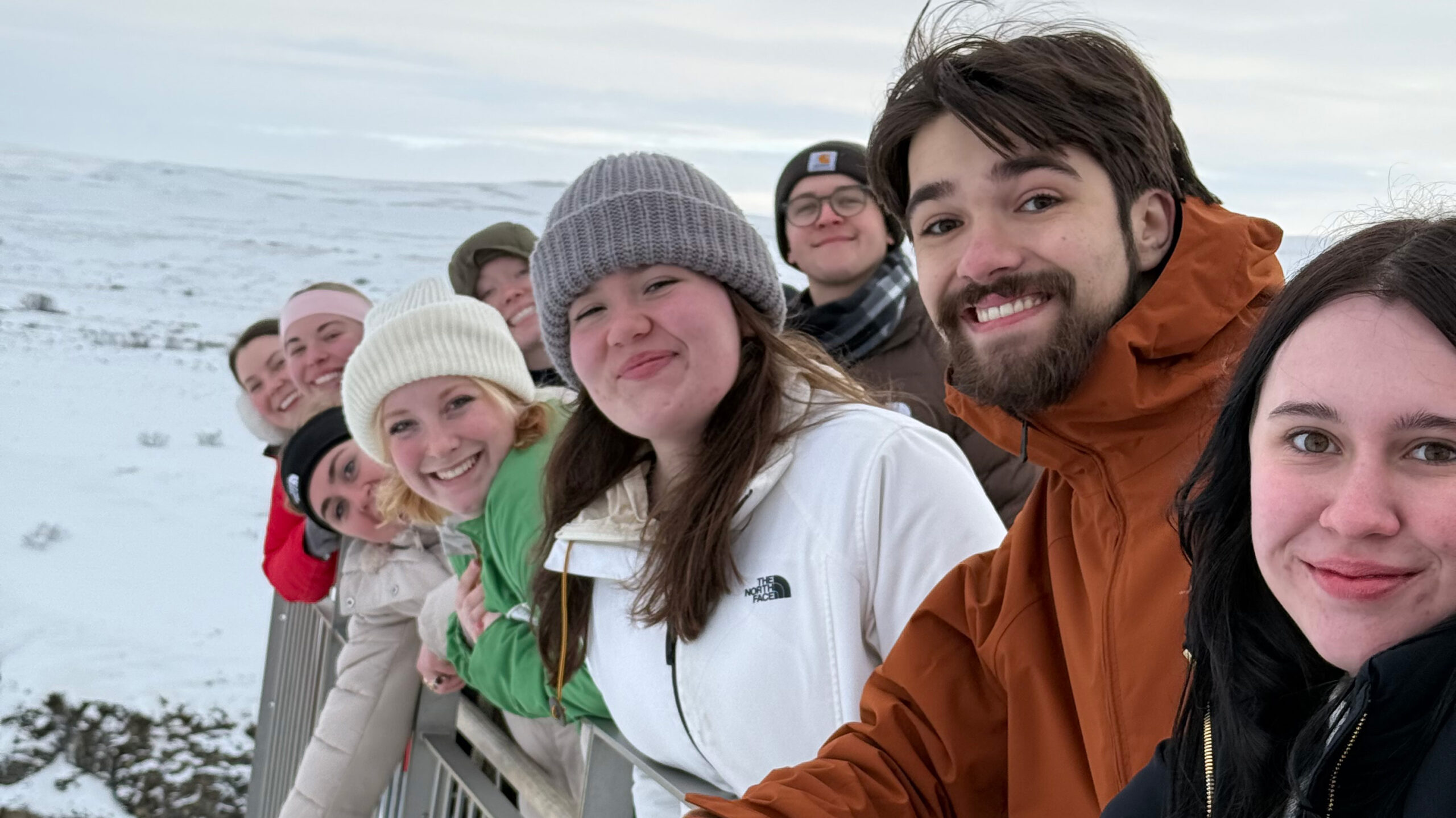 A group of students wearing winter gear and smiling in a line in Iceland