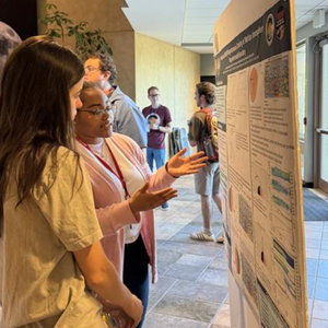 UNC student Jess Johnson explaining her research poster to another person.