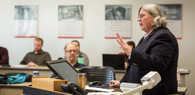 John Clinebell wearing a black coat teaching to a class