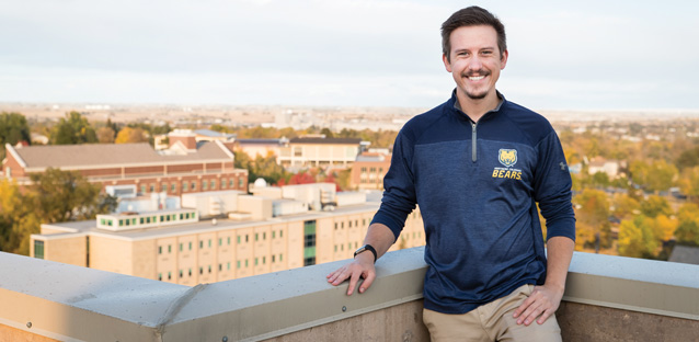 Justin Venman standing near an upper level building ledge smiling outside
