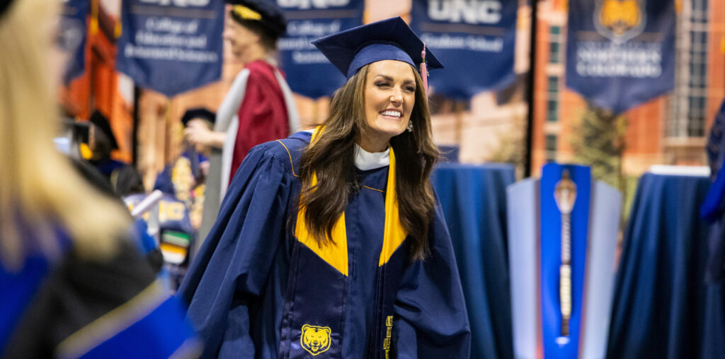 Kim Corban with a big smile on her face, wearing her graduation cap and gown