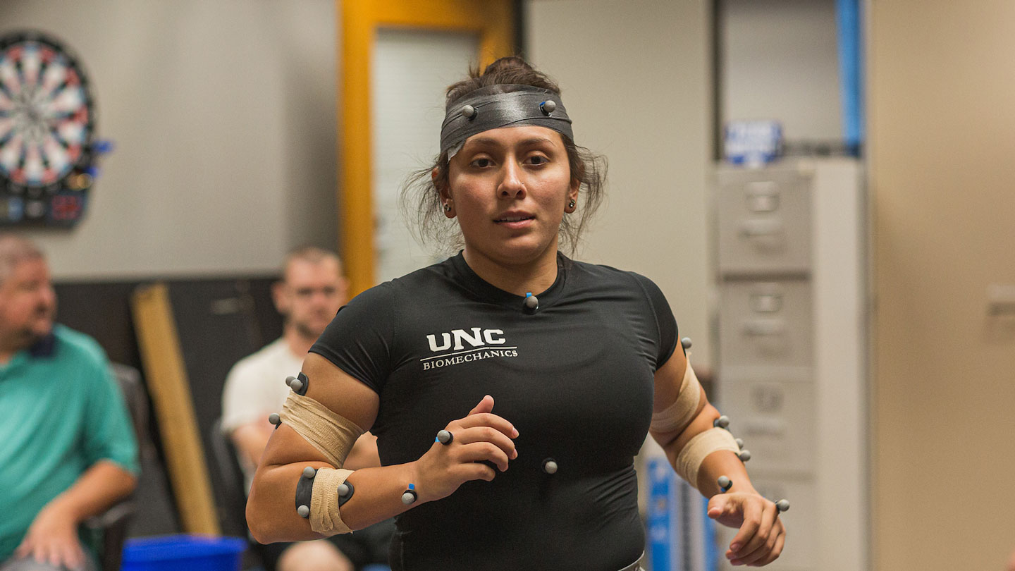 Woman with measuring devices attached, running on treadmill.