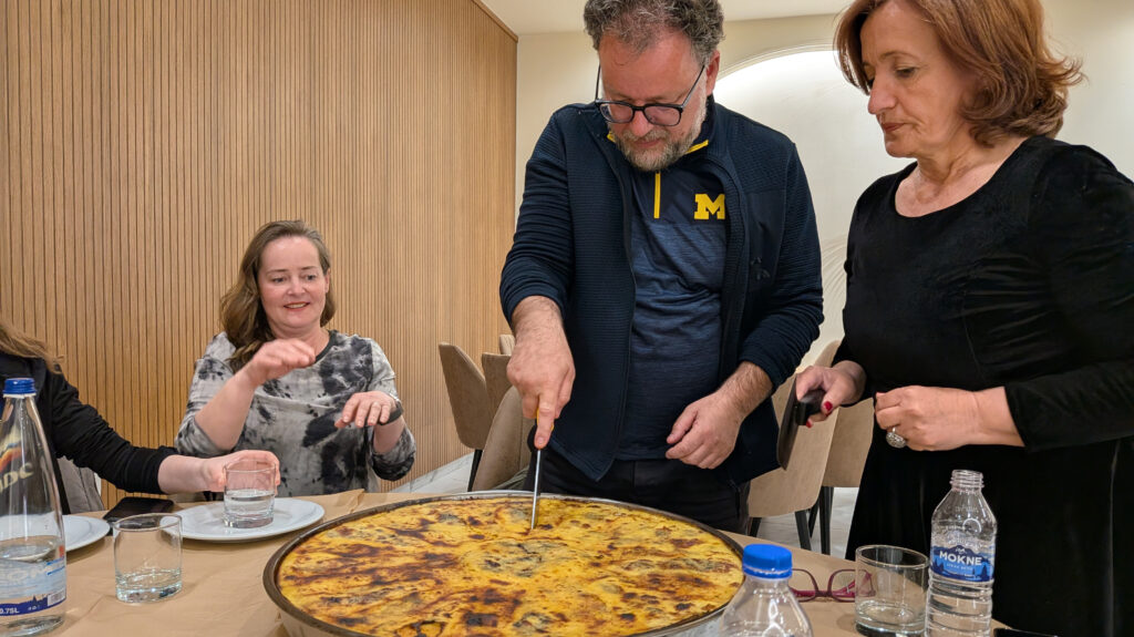 Arsim Canolli, Ph.D., cutting a traditional cornbread flija