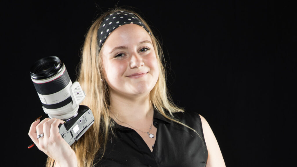 Lexie Martin holding a camera in her right hand and smiling